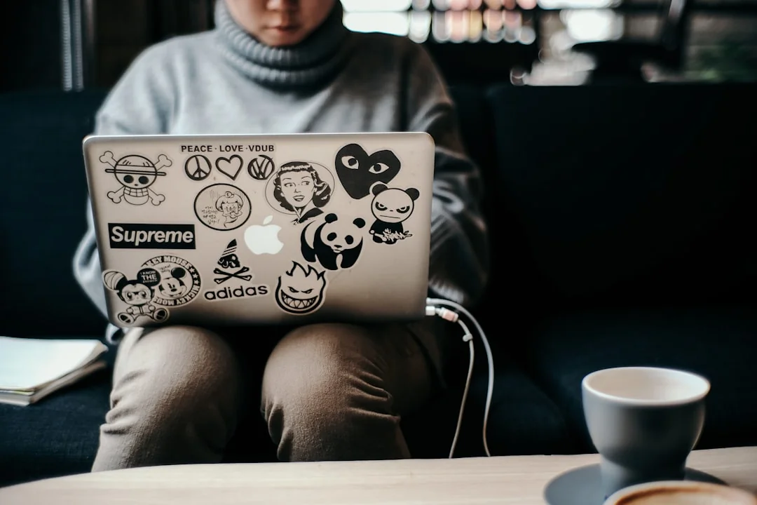 A modern workspace showing hands analyzing marketing data on a laptop and paper documents.